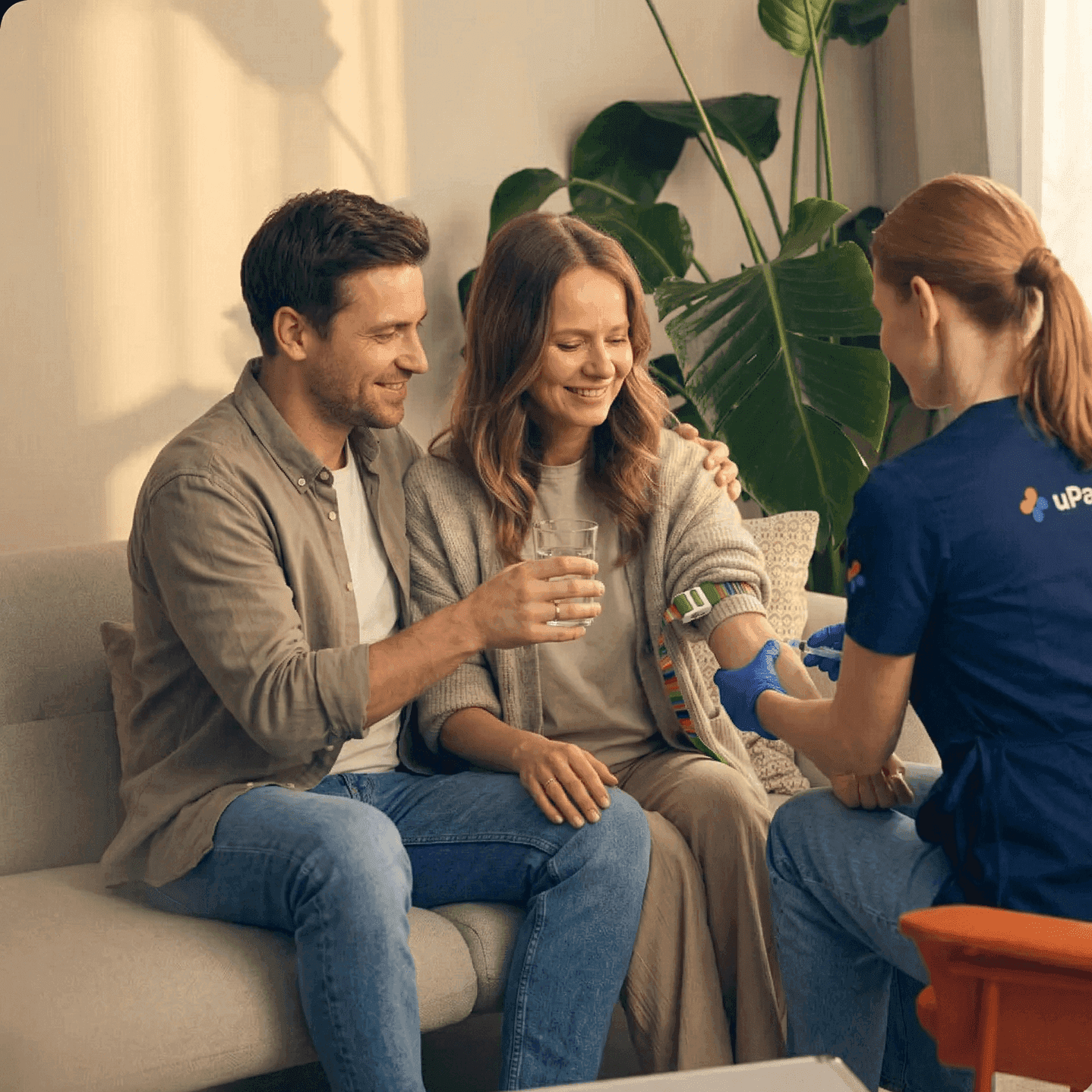 Para siedzi razem na kanapie w domu podczas wizyty medyka — badania krwi dla pary